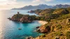 Baie turquoise avec tour génoise, montagnes et voilier
