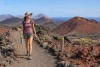 Randonneuse équipée suivant un sentier balisé dans un paysage volcanique calme