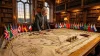 Homme en costume examine une ancienne carte entourée de drapeaux