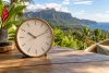 Une horloge analogique générique se détache devant un paysage tropical non localisé.