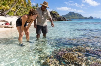 Une voyageuse en chaussures aquatiques observe un récif peu profond avec un guide.