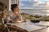 Une voyageuse prépare une escapade côtière avec une carte et des jumelles face à un estuaire.
